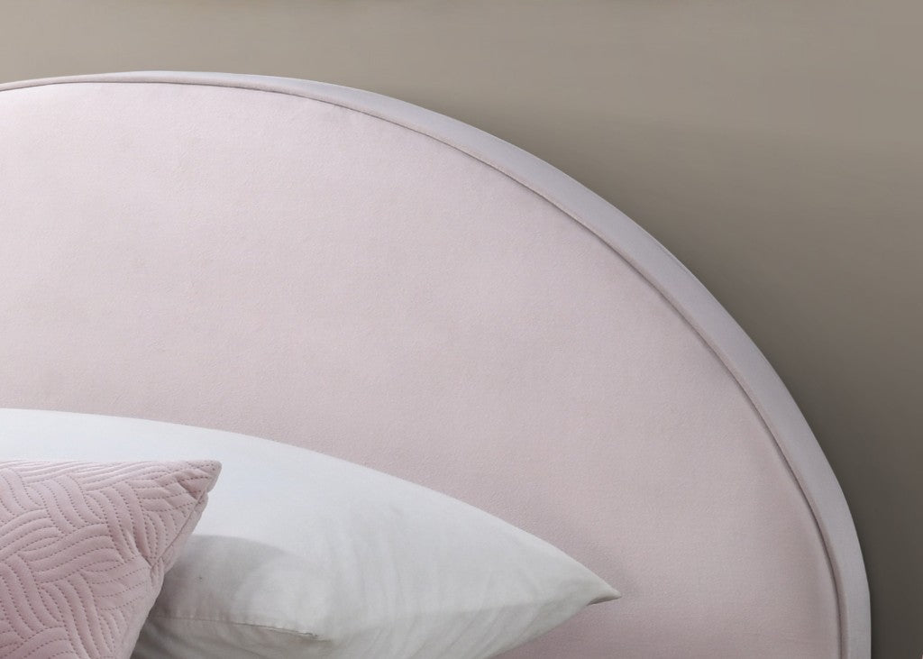 Round headboard with a soft pink finish and a white pillow on a neutral wall.
